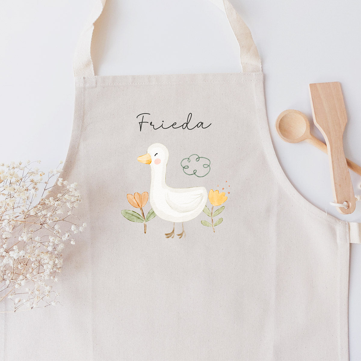 Kinderschürze mit hübscher Gänschen-Grafik und personalisiert mit einem Namen in schwarzer Kalligrafie