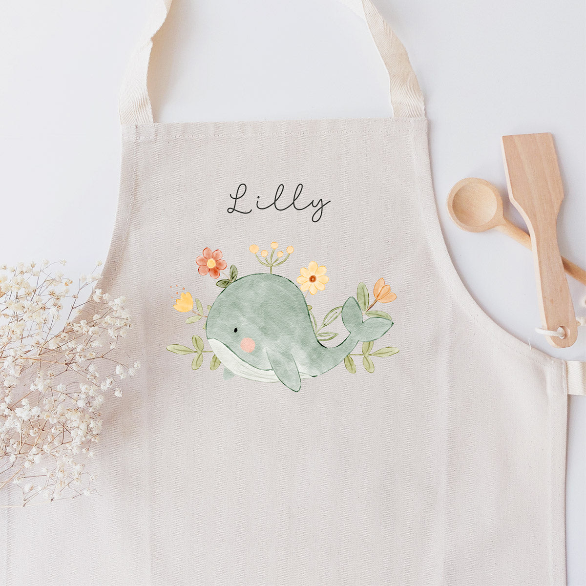 Kinderschürze mit farbenfroher floraler Wal-Grafik 🐳 und personalisiert mit einem Namen in schwarzer Kalligrafie